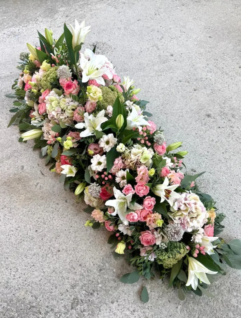 Dessus de cercueil mélange de lys blanc, roses branchues roses, hortensia roses, trachelium, allium
